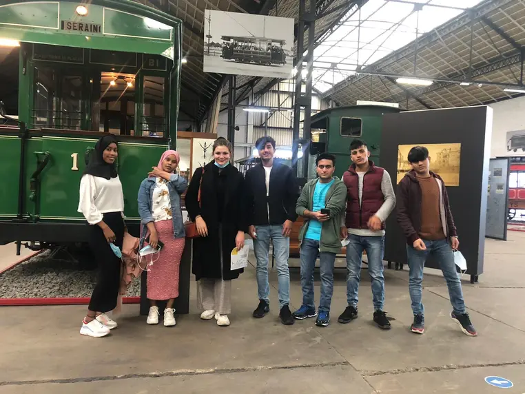 Un groupe de jeunes devant une ancienne motrice de tram, au musée des transports.