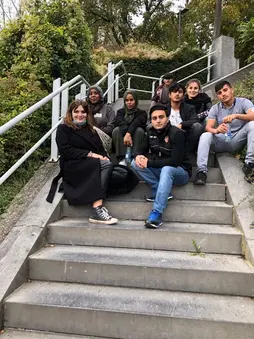 Un groupe de jeunes assis dans un escalier extérieur, pendant une pause.