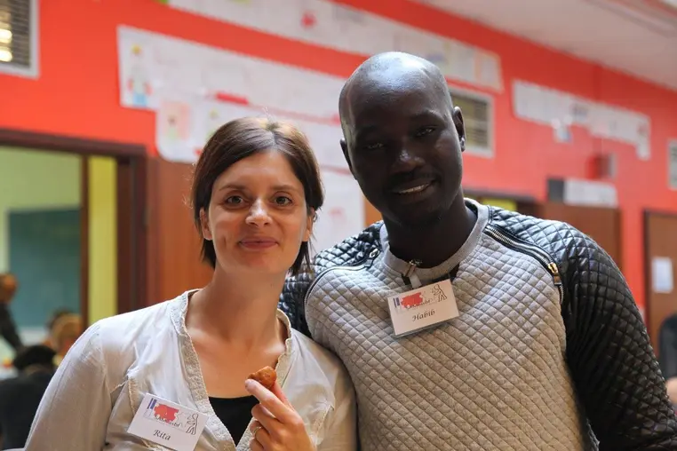 Deux participants souriants, badge nominatif SAM asbl au revers.