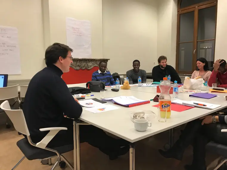 Réunion de travail autour d'une grande table, vue depuis l'autre extrémité.